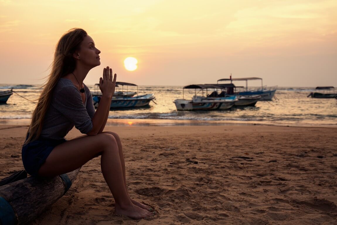 Молодая красивая девушка молится у океана