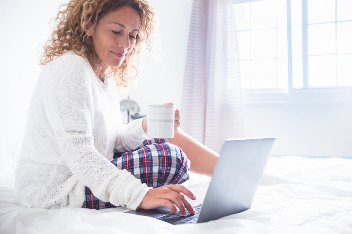 Красивая женщина использует портативный компьютер дома утром на кровати