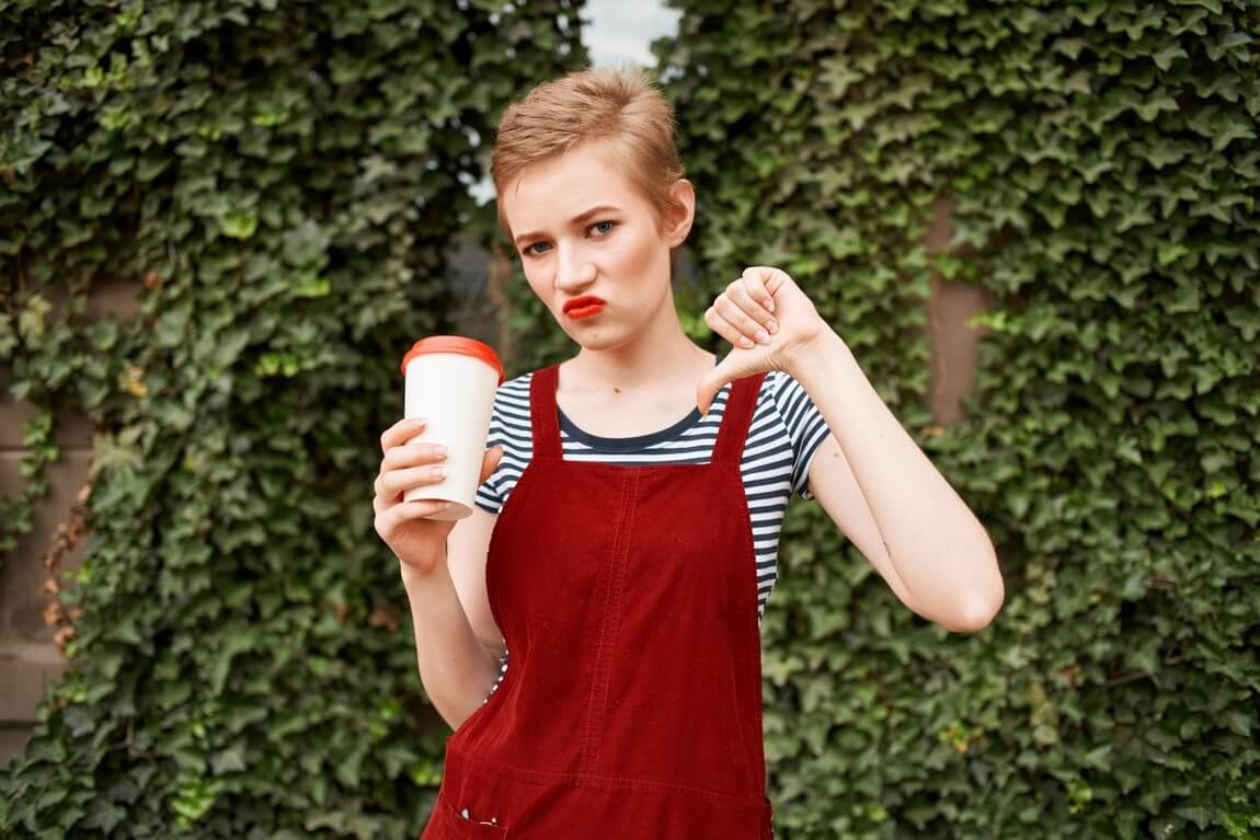 Симпатичная коротковолосая женщина с чашкой кофе на свежем воздухе