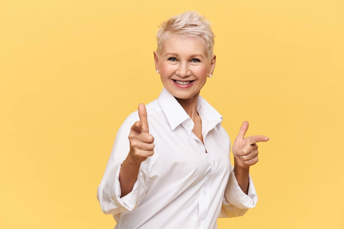 Счастливая пятидесятилетняя женщина в стильной белой рубашке