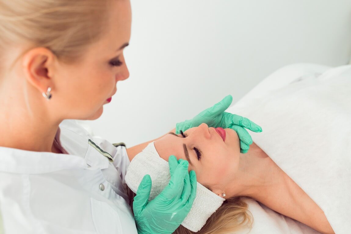 Косметолог на работе молодая женщина-врач готовит пациента к косметическим процедурам