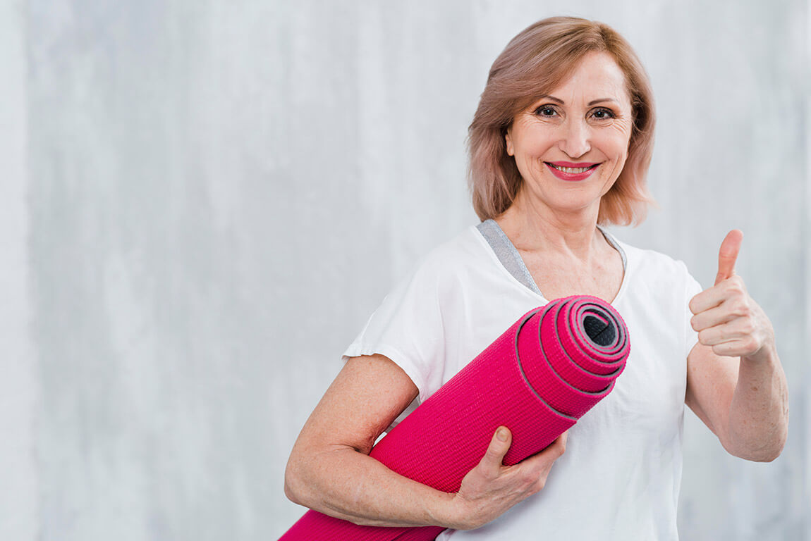 Женщина стоит с ковриком для йоги
